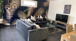 Un salon moderne avec un canapé d’angle, un téléviseur à écran plat et une table basse.