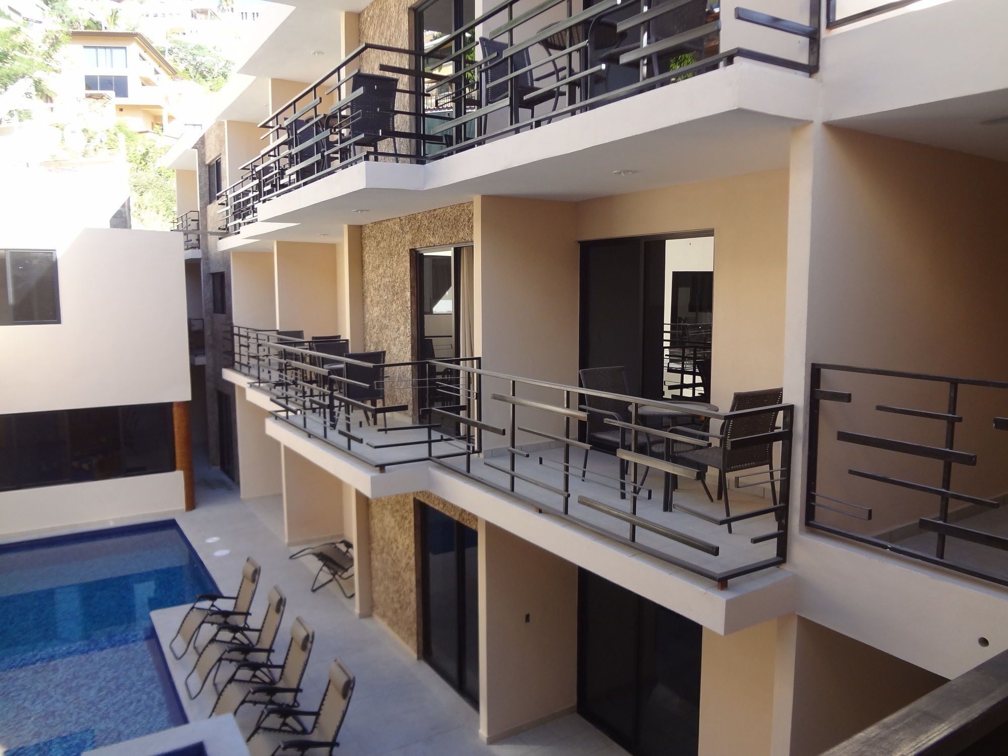A multi-story hotel with balconies, a swimming pool, and outdoor seating.