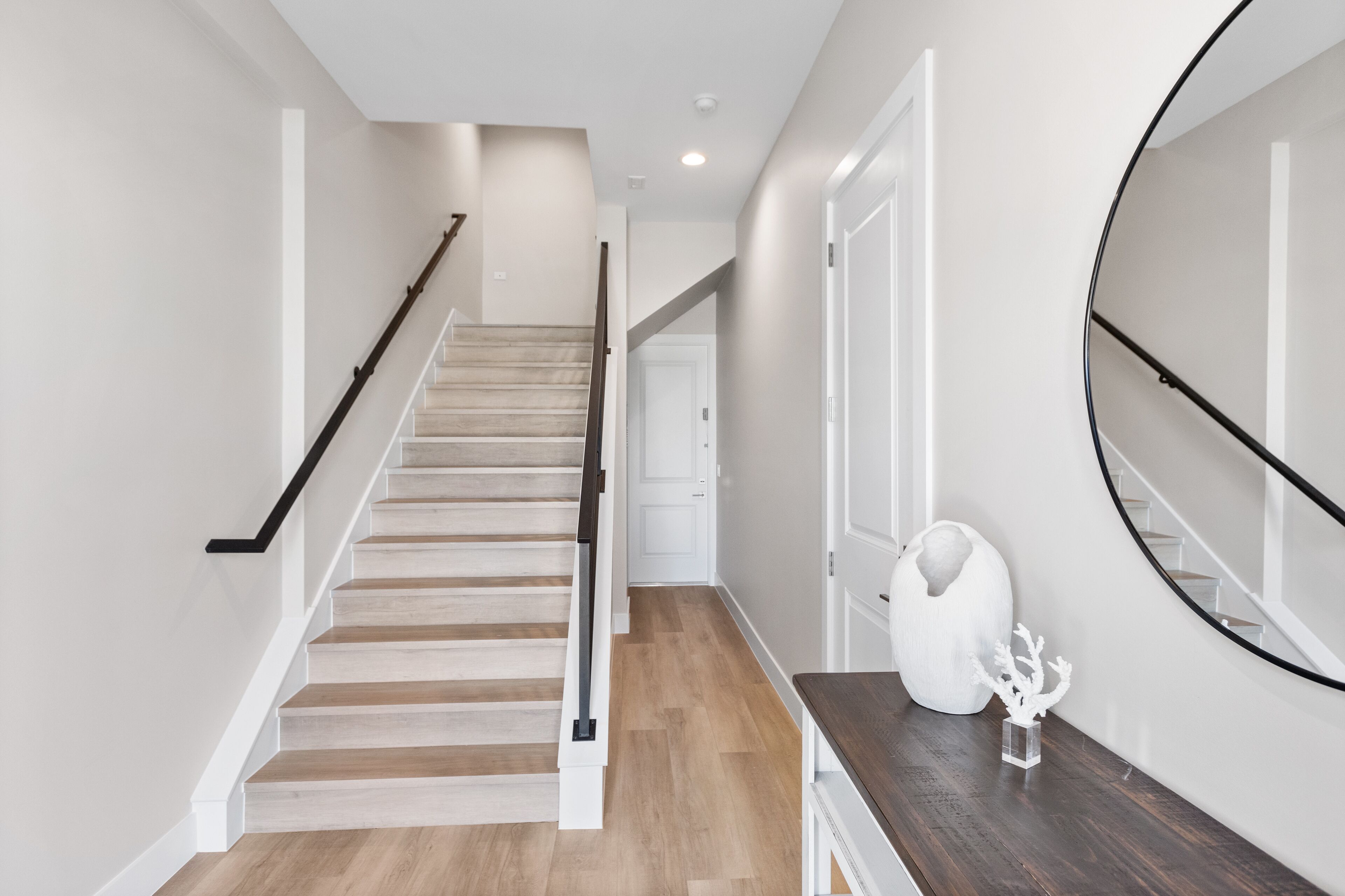 A modern staircase with wooden steps and black handrails, leading to a white door.