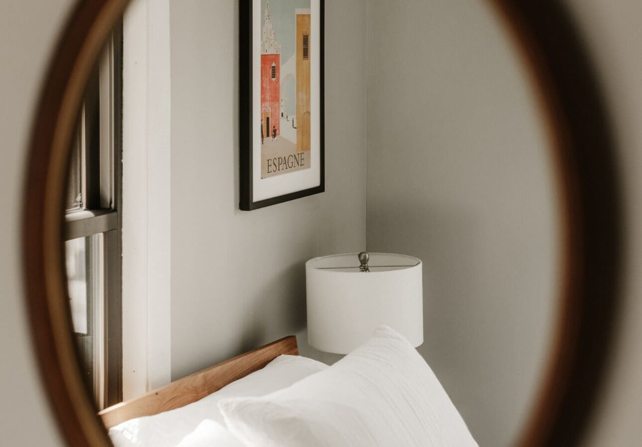 A bedroom with a bed, a nightstand, a lamp, and a framed picture on the wall.