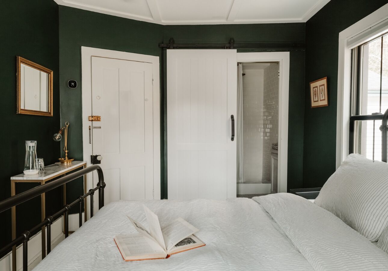 Un dormitorio con cama, mesita de noche con lámpara, armario y ventana.
