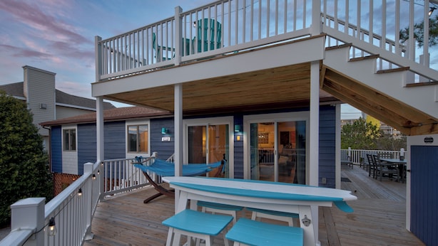A wooden deck with a table and chairs, a hammock, and a covered area with a view of the house. - Steps to Fenwick Island Beach, Ocean&Bay views, hot tub. Pet & family friendly! (Fenwick Island)