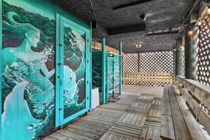 A wooden deck with a mural of a wave and a mermaid, a wooden bench, and a lattice fence.
