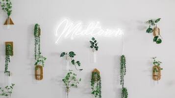 A wall with a neon sign spelling "Midtown" and various hanging plants.