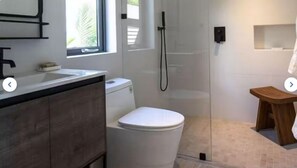 Bathroom features a toilet, glass-enclosed shower, and a stool.