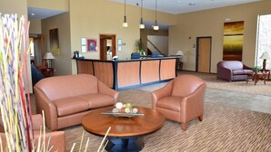 A hotel lobby with a reception desk, two leather sofas, a coffee table with decorative items, and a large painting on the wall. - Cobblestone Inn and Suites Newton (Newton)