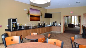 A hotel lobby with a coffee station, seating area, and a TV mounted on the wall. - Cobblestone Inn and Suites Newton (Newton)