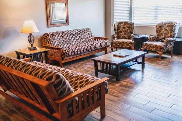 A living room with a patterned sofa, two armchairs, a coffee table, and a lamp.