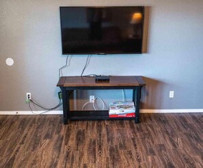 A flat-screen TV mounted on a wall above a wooden entertainment center with a remote control on top.