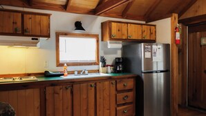 Cocina de cabaña de madera con refrigerador empotrado, ventana y armarios de madera.