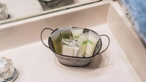 A metal basket containing several white bottles with the label "ECO" on a bathroom counter.