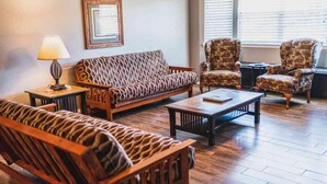 A living room with patterned sofas, armchairs, a coffee table, and a lamp. - Lake Texoma Six-Plex Main Room (Mead)