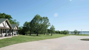 A building with a patio area, outdoor seating, and a view of a body of water. - Lake Texoma Six-Plex Main Room (Mead)