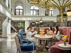 A spacious lobby with a high ceiling, a central round table with a tiered dessert display, and seating areas with plush sofas and chairs. - Mercure Dalat Resort (Lam Vien - Da Lat)