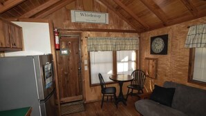 L’intérieur d’une cabane en bois comprend un coin repas, un réfrigérateur, un canapé et une horloge murale.
