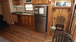 Une cuisine de style rustique, avec des murs en bois, un réfrigérateur, un four à micro-ondes et des armoires en bois.