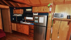 Una cocina compacta con armarios de madera, un refrigerador de acero inoxidable y un microondas en un estante.