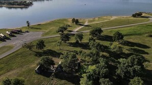 An aerial view of a golf course with a lake, a bridge, and a parking area with tents. - Lake Texoma Cedar Cabin - Striper King (Mead)