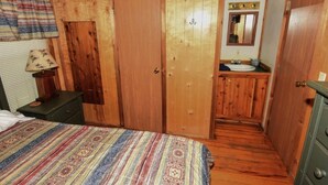 A wooden room with a bed, a dresser, a mirror, and a sink. - Lake Texoma Cedar Cabin - Striper King (Mead)