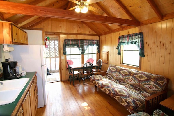 Una cabaña acogedora con interior de madera, un comedor y un sofá.