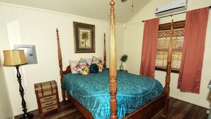 A four-poster bed with a blue bedspread, a wooden floor, a wall-mounted air conditioner, and a framed picture. - Lake Texoma Lakefront Cabin - Texoma Breeze (Mead)