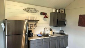 A kitchen with a stainless steel refrigerator, a coffee maker, a sink, and a microwave.