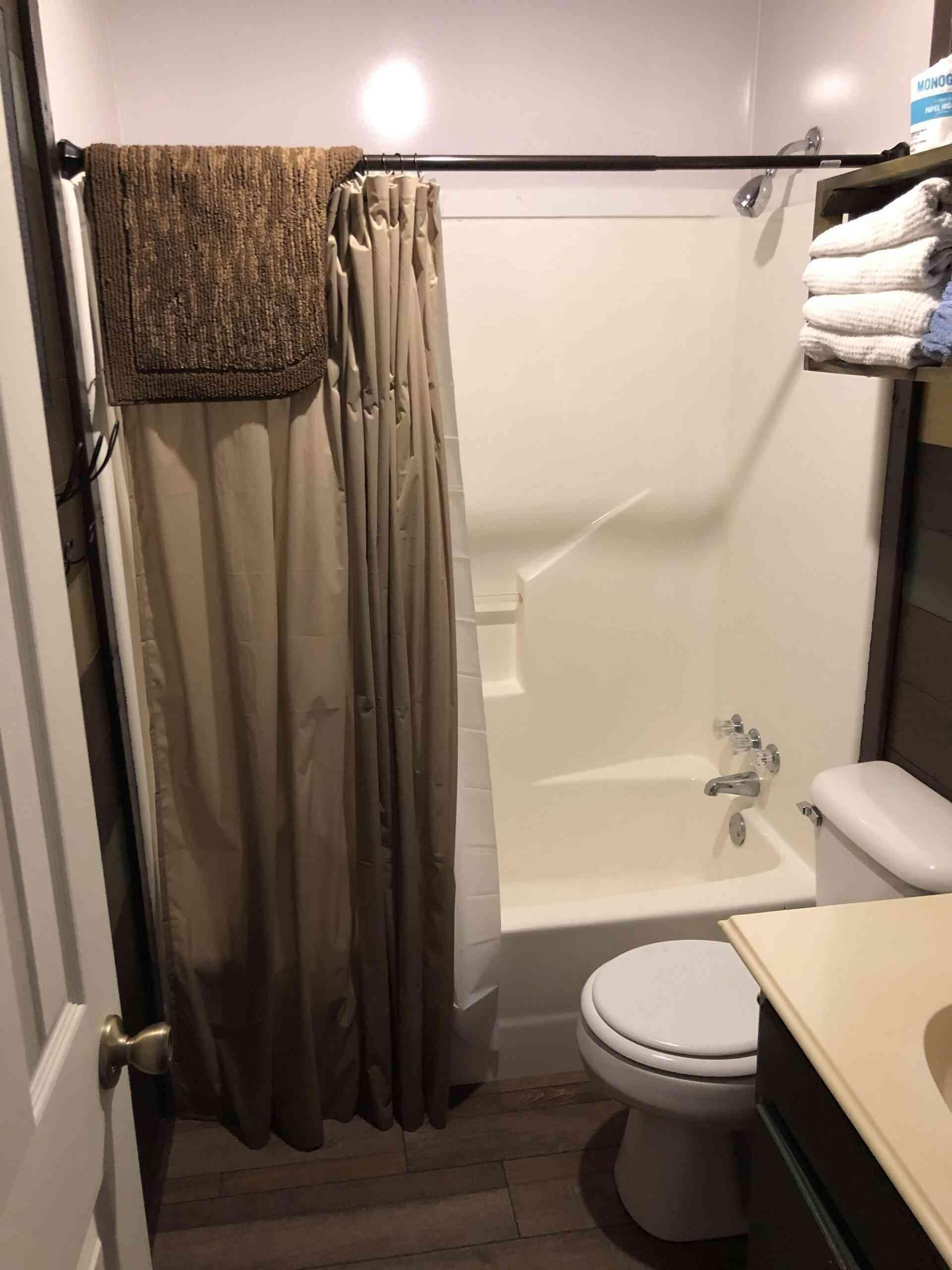 Un baño con ducha, inodoro y un perchero con toallas.