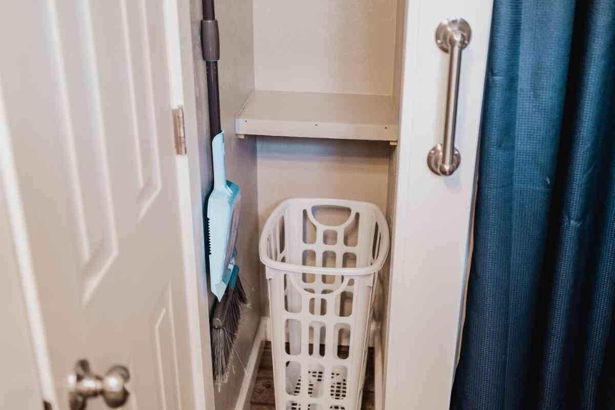 A laundry basket in a bathroom with a shower curtain and a towel rack.