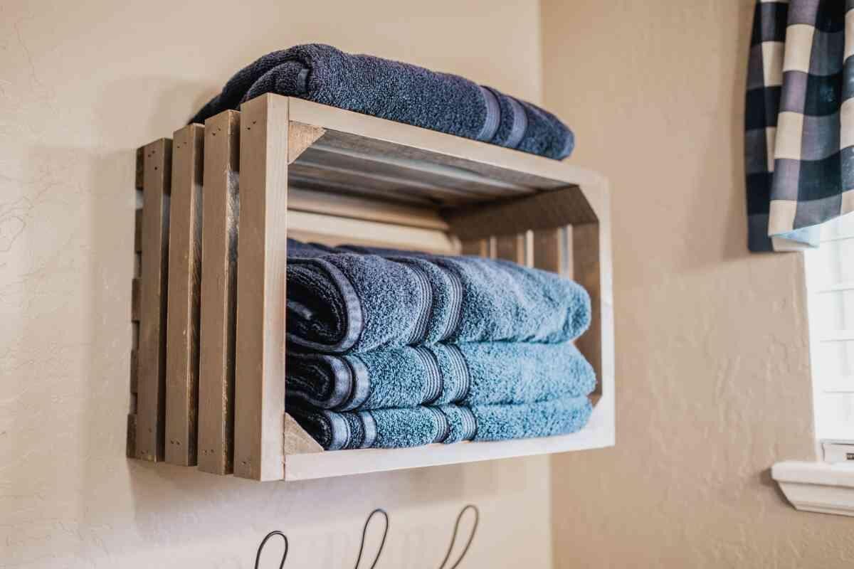 Ein Holzregal mit gefalteten Handtüchern an einer Wand.