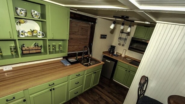 A compact kitchen with green cabinets, a wooden countertop, and a built-in sink.