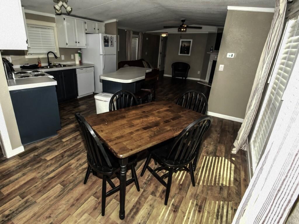 Een compacte keuken met witte kasten, een centraal eiland en een eettafel met stoelen.