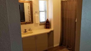 A bathroom with a sink, mirror, window, and shower curtain. - Lake Texoma Lakeside Cottage (Mead)
