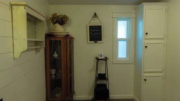A room with a wooden cabinet, a small window, a chalkboard with a message, and a black luggage trolley.