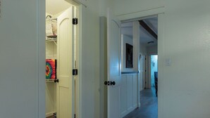 A hallway with white doors, a closet with shelves, and a wooden floor. - Lake Texoma Vacation Home The Farm House (Mead)
