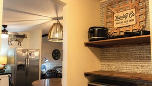 A kitchen with a refrigerator, microwave, and a hanging light fixture. - Lake Texoma Vacation Home The Farm House (Mead)