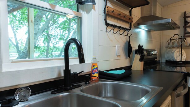 A kitchen with a double sink, a window, and a view of trees outside. - Lake Texoma Vacation Home The Farm House (Mead)