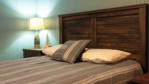Uma cama com cabeceira de madeira, colcha listrada e dois travesseiros.