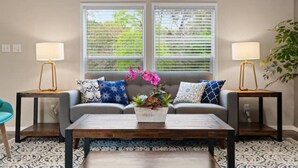 A living room with a grey sofa, two side tables with lamps, a coffee table, and a patterned rug. - Peaceful Cabin - 8 acres Ranch Dripping Springs Venues & Breweries (Dripping Springs)
