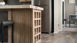 A kitchen with wooden cabinetry, a stainless steel refrigerator, and a bar area with stools. - Peaceful Cabin - 8 acres Ranch Dripping Springs Venues & Breweries (Dripping Springs)