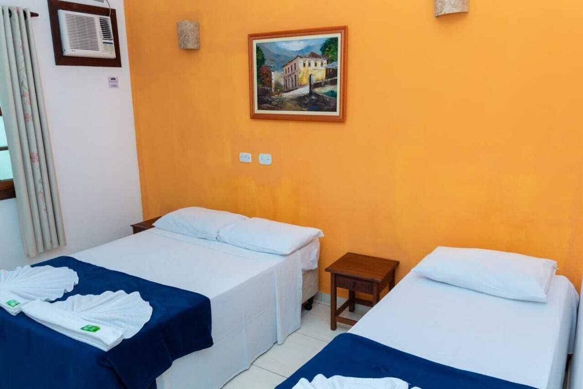 A hotel room with two beds, a painting on the wall, and a small table.