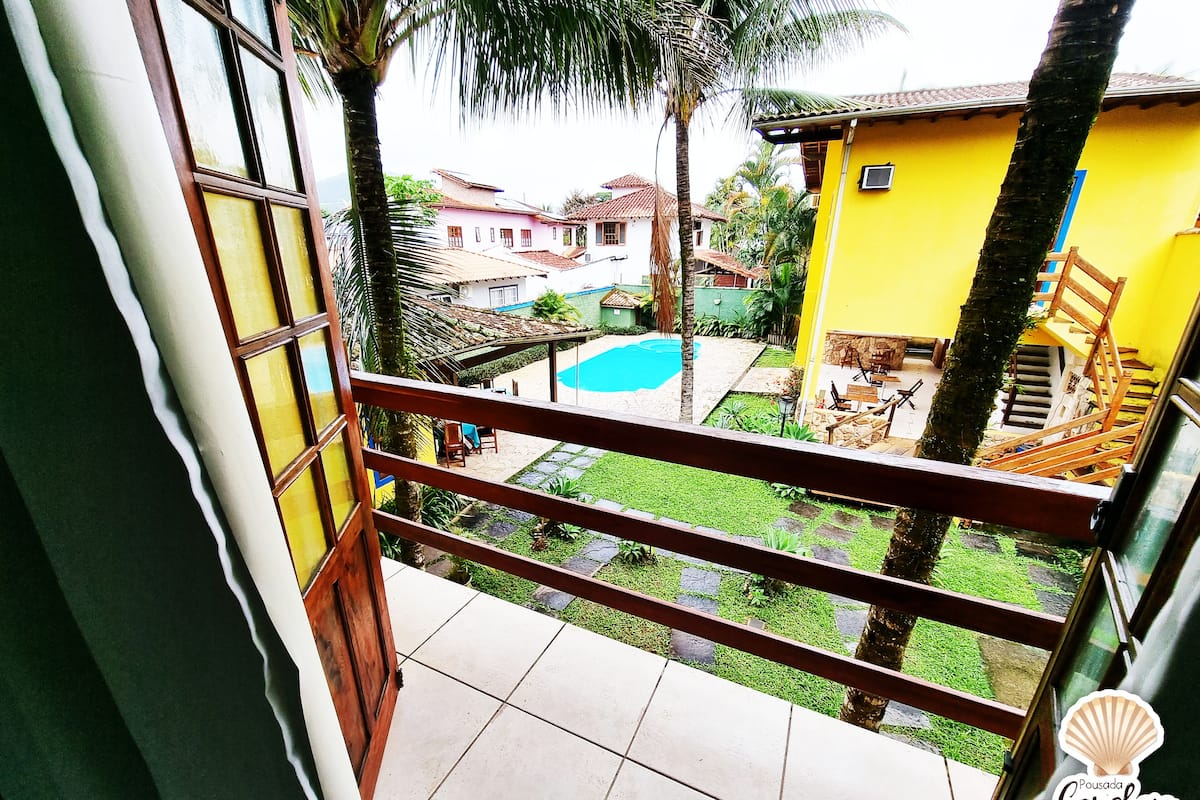 A view from a balcony overlooking a swimming pool, a yellow building, and a staircase.
