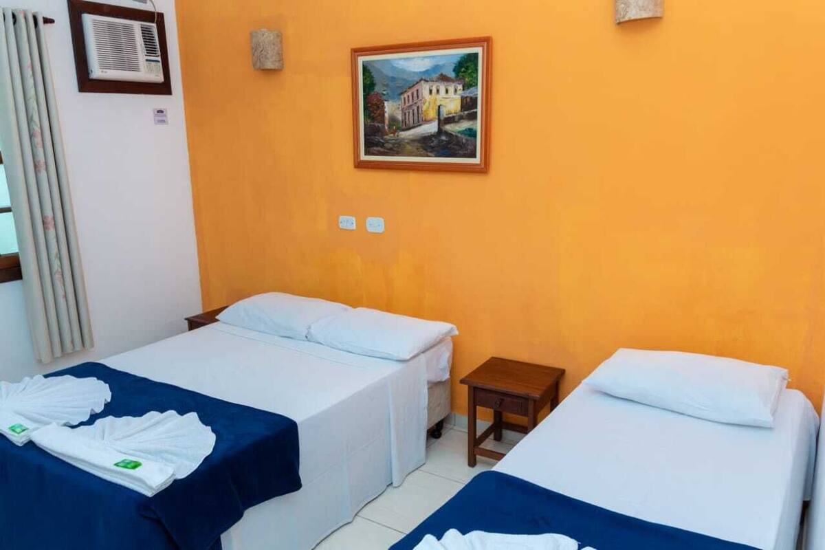 A hotel room with two beds, a painting on the wall, and a small table.