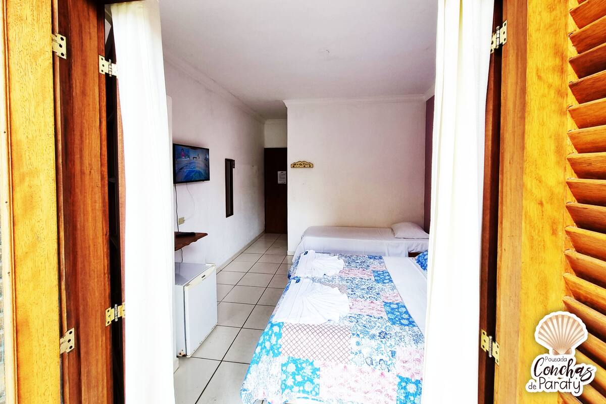 A bedroom with a bed, a TV, a desk, and a wardrobe.