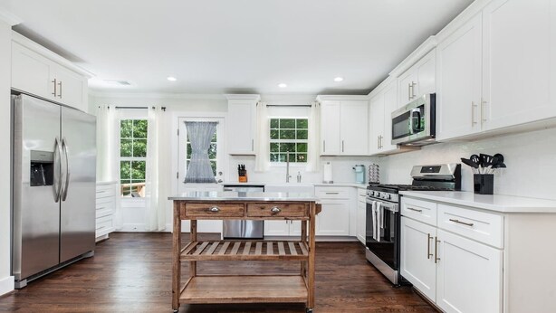 A modern kitchen with white cabinetry, stainless steel appliances, and a wooden island. - Crestwood Contemporary - Minutes to Downtown! (Birmingham)
