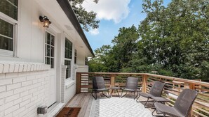 A covered outdoor area with a wooden deck, wicker chairs, and a welcome mat. - Crestwood Contemporary - Minutes to Downtown! (Birmingham)