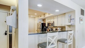Een moderne keuken met witte kastjes, een centraal eiland met barkrukken en ingebouwde apparatuur.