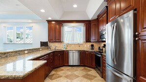 Una cocina con armarios de madera, un refrigerador de acero inoxidable y un lavavajillas.