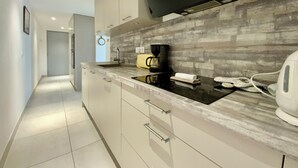 Een moderne keuken met een flatscreen televisie, een koffiezetapparaat en een waterkoker op het aanrecht.