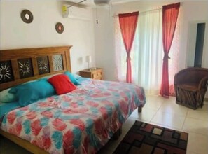 Cozy retreat with a large bed, nightstand, and comfortable chair.