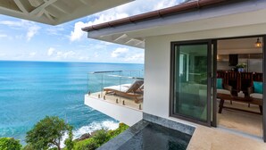 Una casa moderna con un balcón de cristal que da al océano.